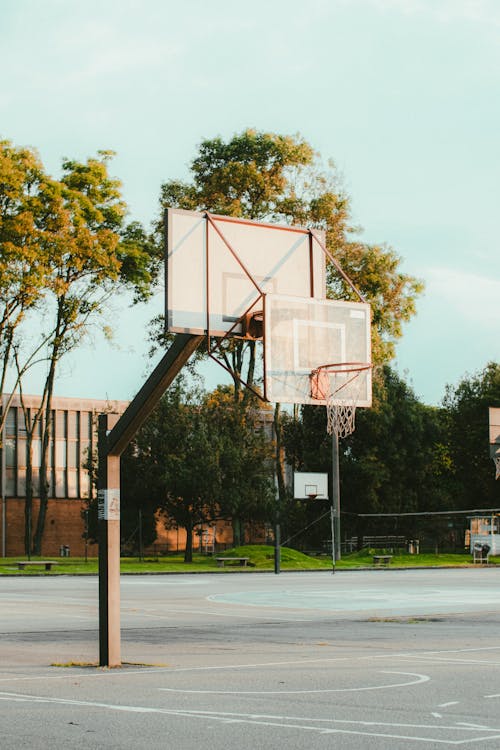 Basketball Court Near Green Trees Under a Blue Sky