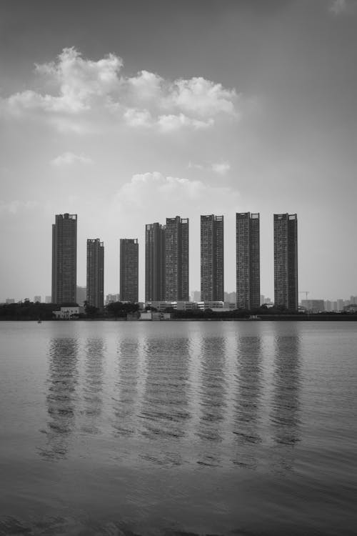 Grayscale Photo of High Rise Buildings Across the River 