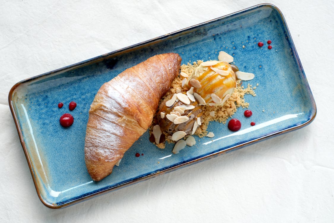 A Croissant and Ice Cream on a Ceramic Plate