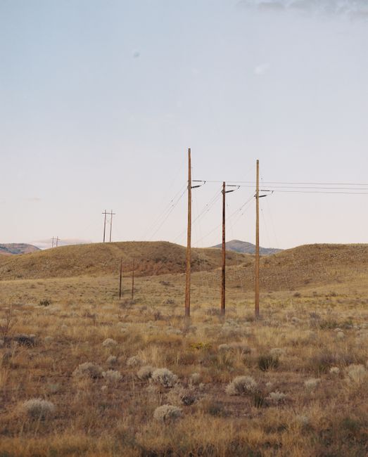 Beautiful rural landscape with power lines crossing grassy hills under a clear sky.