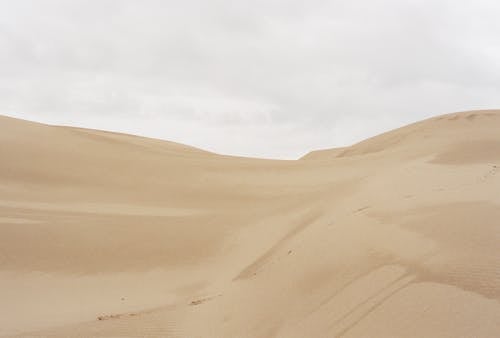 Sand Dune on Desert Under White Sky