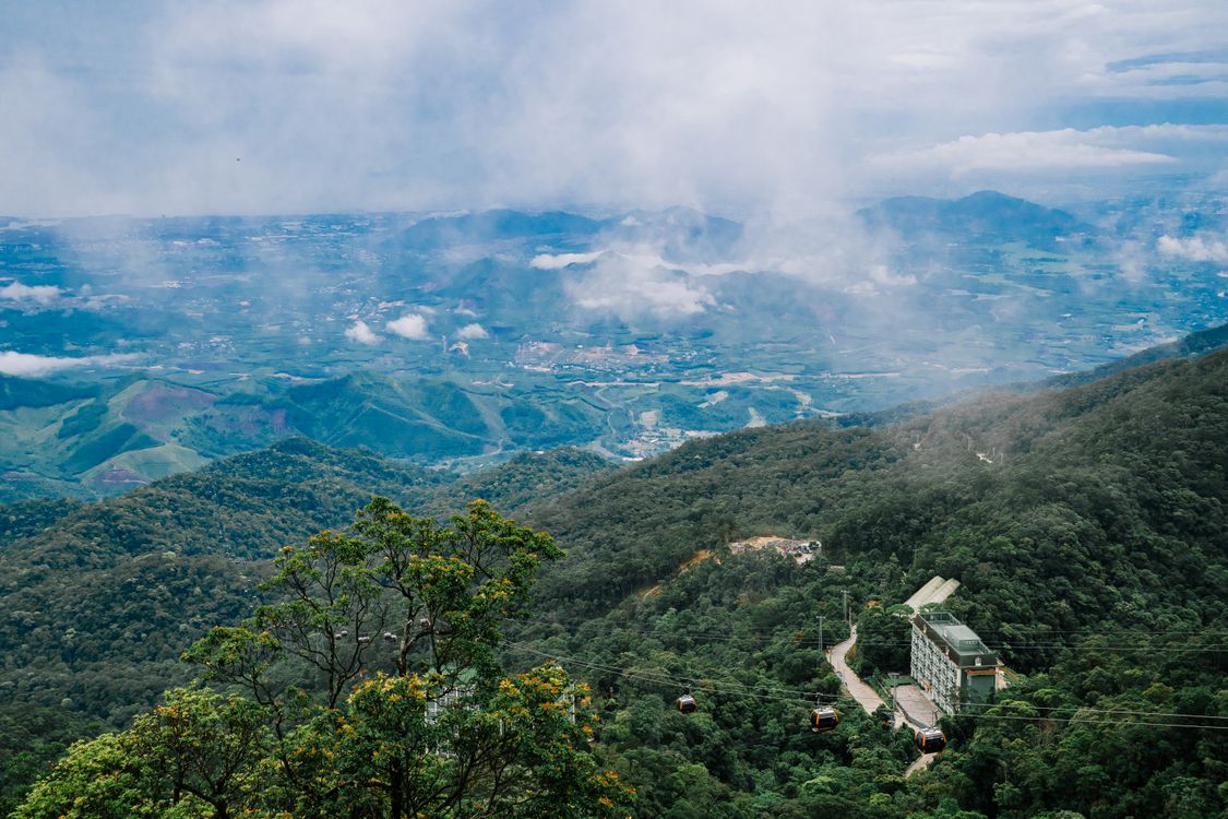 Free A breathtaking view of cable cars gliding over lush green mountains beneath a cloudy sky. Stock Photo