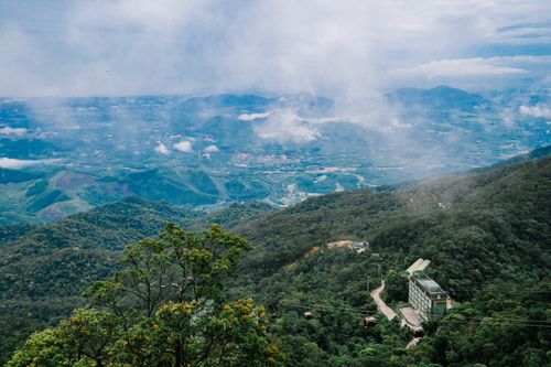 Free A breathtaking view of cable cars gliding over lush green mountains beneath a cloudy sky. Stock Photo