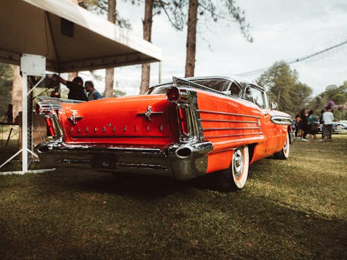 Close-up Photo of Red Vintage Car on Green Grass 