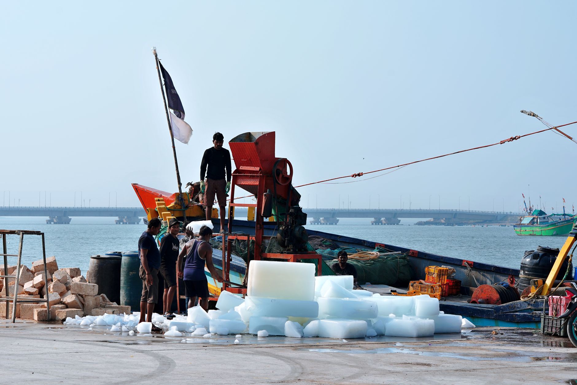 Workers loading ice blocks onto a fishing boat at Diu Port in India. Vibrant harbor scene.