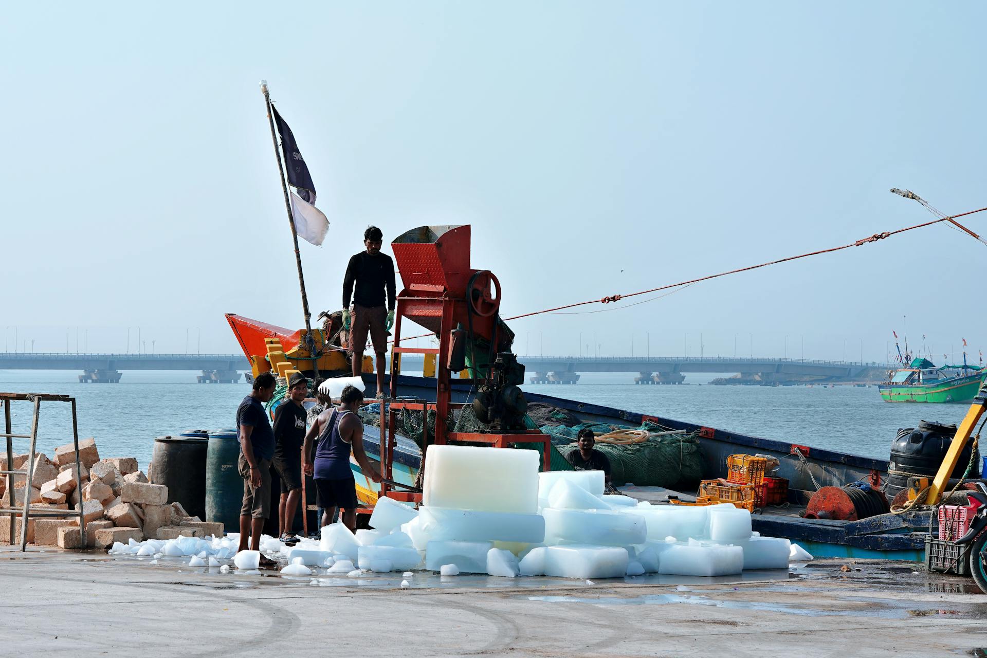 Workers loading ice blocks onto a fishing boat at Diu Port in India. Vibrant harbor scene.
