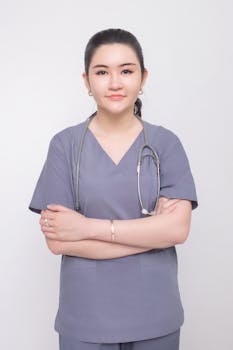 Portrait of a confident female nurse in medical scrubs with arms crossed.