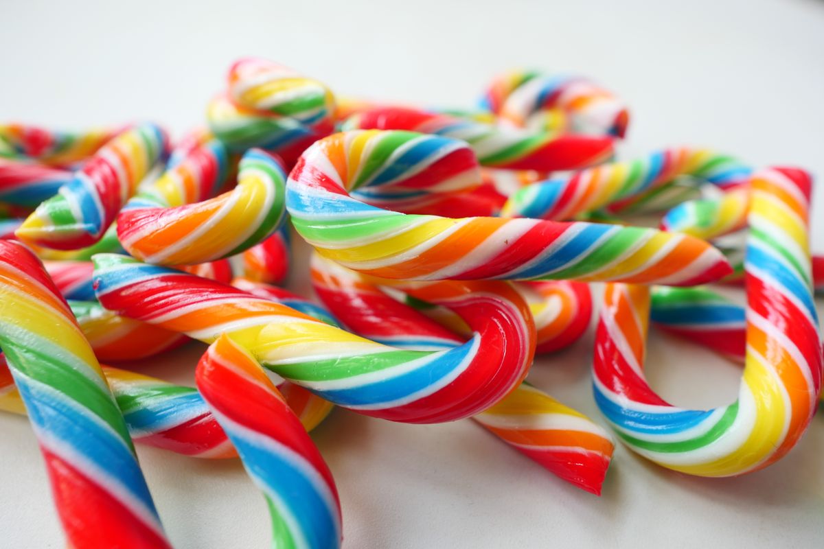 Vibrant and colorful candy canes arranged on a white surface, perfect for festive themes.