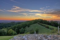 迷人的乡村景观，山丘、树木与充满活力的日落天空交相辉映