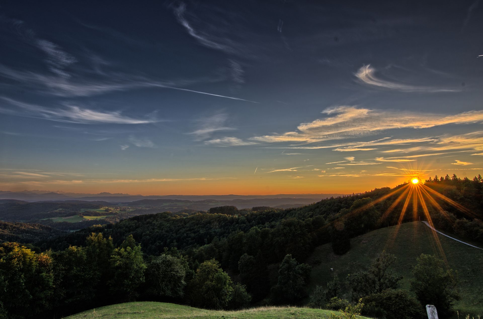 A stunning sunrise over rolling hills and dense forests, capturing nature's beauty.