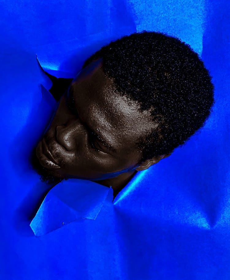 Blue Paper Punctured By Man Head