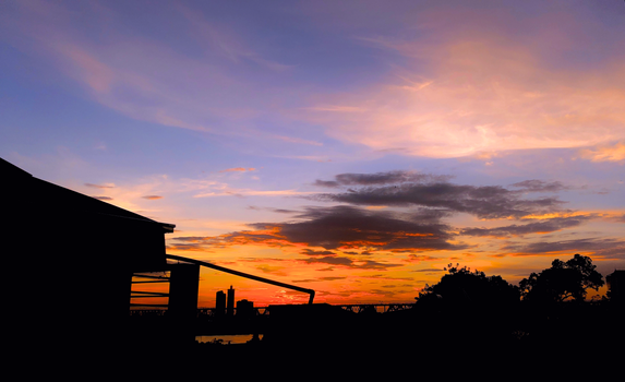 Vibrant sunset over Hanoi with silhouetted cityscape and clouds.