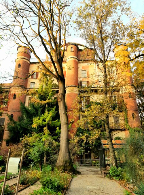Free Charming historic red brick building surrounded by vibrant autumn trees in Milan. Stock Photo