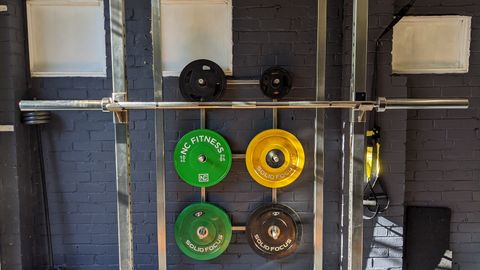 A well-equipped home gym featuring a squat rack, weights, and a bench.
