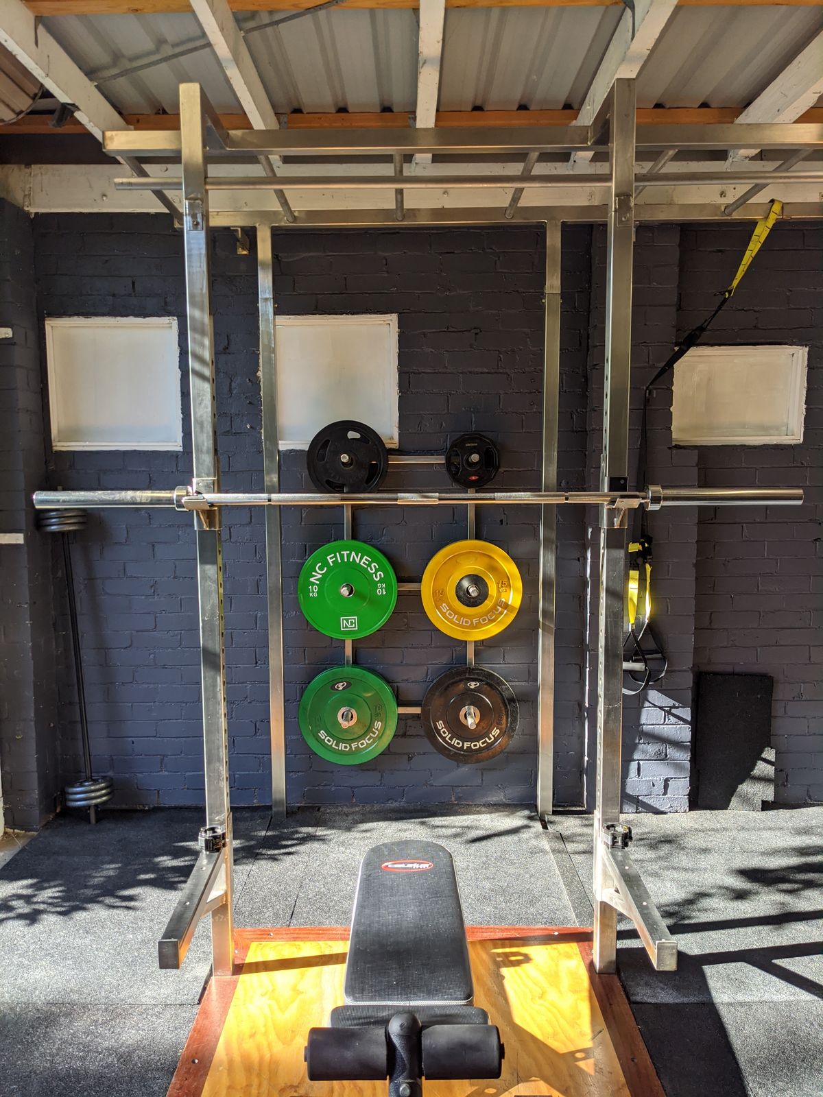 Strength training setup with squat rack weights and workout bench