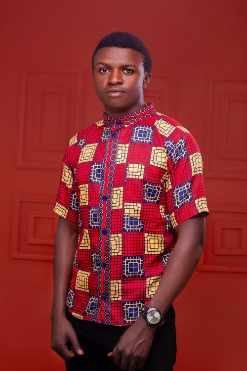 Free Portrait of a man in vibrant traditional African attire against a red background Stock Photo