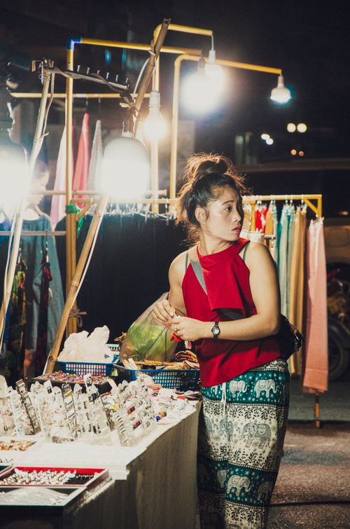 Free A young woman shops for accessories at a vibrant night street market, under bright lights. Stock Photo