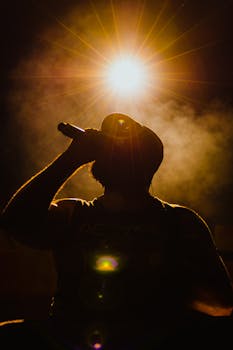 Dramatic silhouette of a singer with a microphone under a bright spotlight.