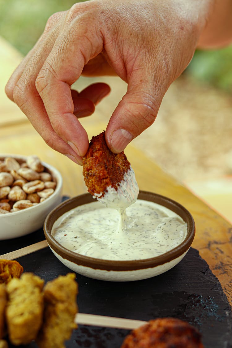 Hand Dipping Falafel In Sauce