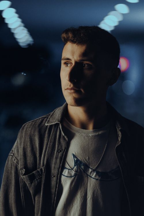 Free Portrait of a young man in casual clothing with moody lighting at night. Stock Photo