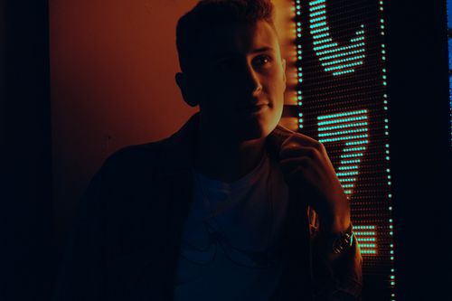 Free Atmospheric portrait of a young man illuminated by vibrant neon lights at night. Stock Photo
