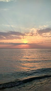 Peaceful ocean sunset scene with colorful sky and gentle waves, capturing serene tranquility.