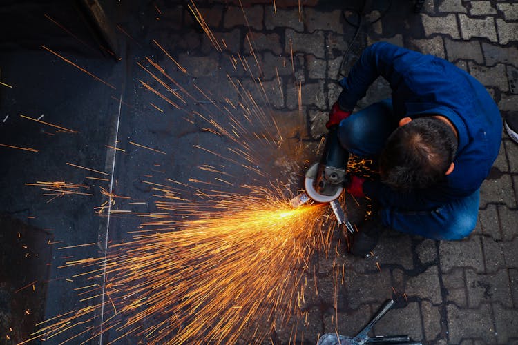 High Angle Shot Of A Person Grinding Metal