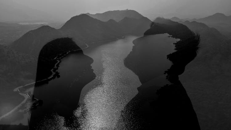 Silhouette Of Woman And Man Face Over River In Black And White