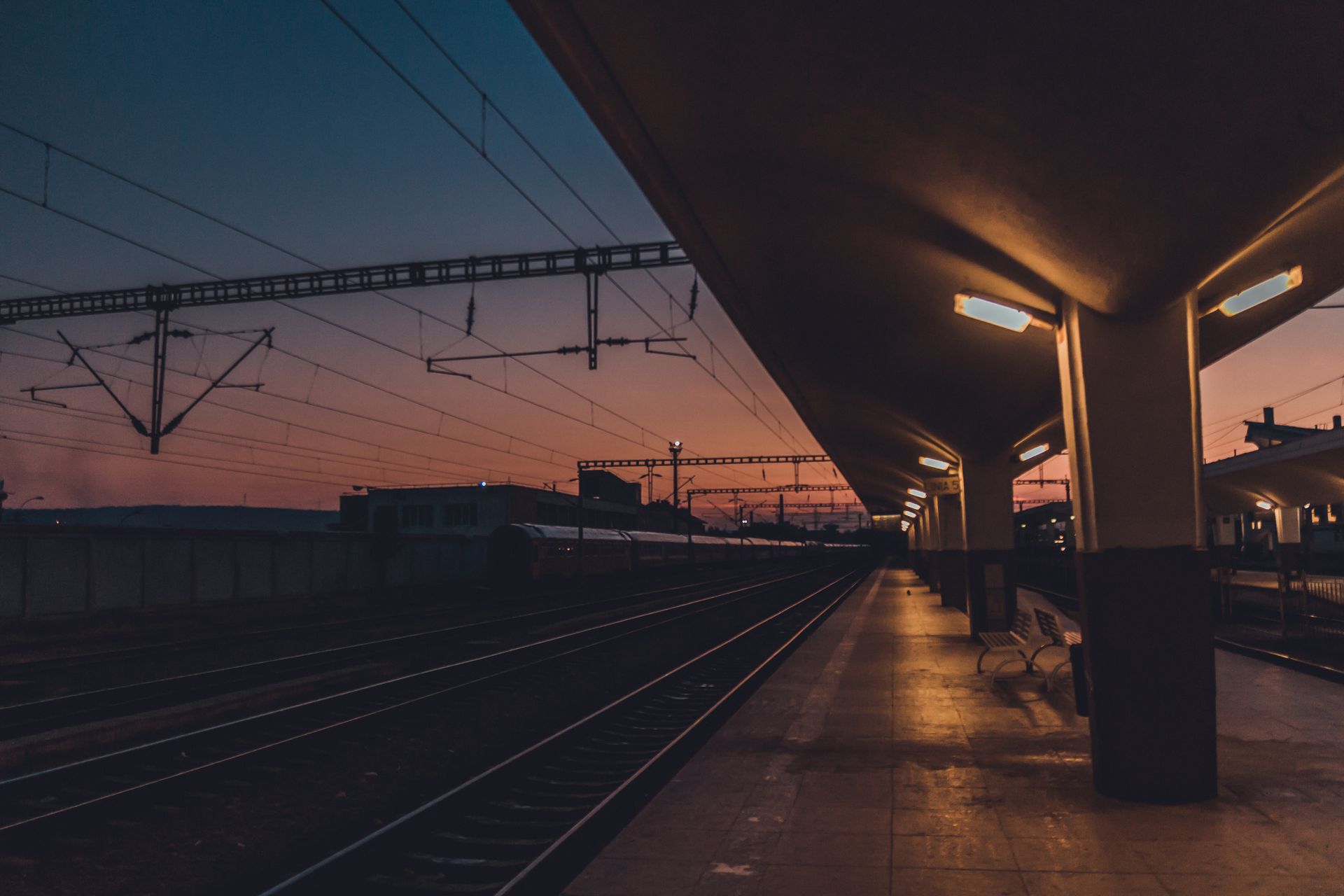 Captivating sunset view of Cluj-Napoca railway platform with vibrant sky and modern lighting.