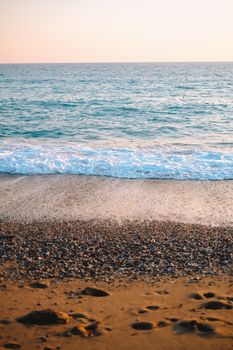 Tranquil ocean waves at a sunset beach with soft sand and gentle water reflections.