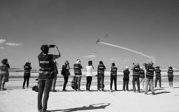 A Group Of People Taking Pictures Of A Group Of Airplanes Flying 