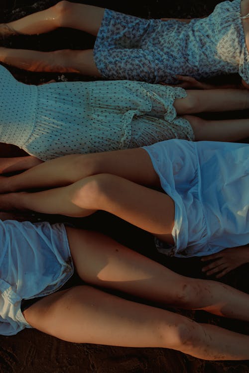 Free Women in Dresses Lying Down on Beach Stock Photo