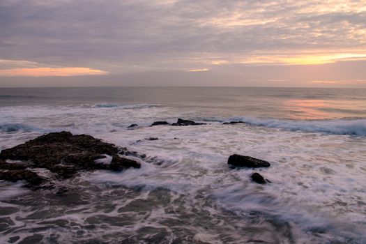Tranquil seascape at sunrise on Dolphin Coast, KZN, South Africa, featuring gentle waves and rocky shores.