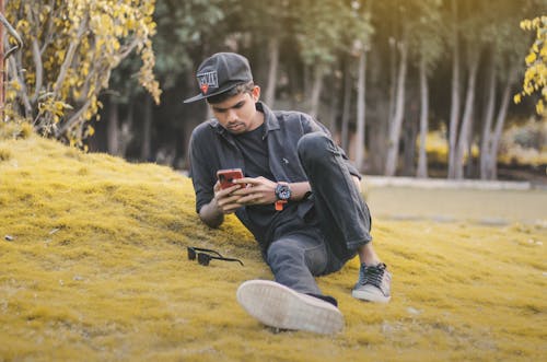 Man Sitting In A Park And Using A Phone