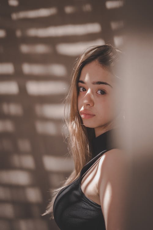 Woman in Black Tank Top Leaning on the Wall