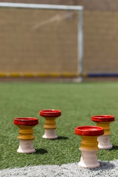 Close-up of training cones on a soccer field with goalposts in the background.