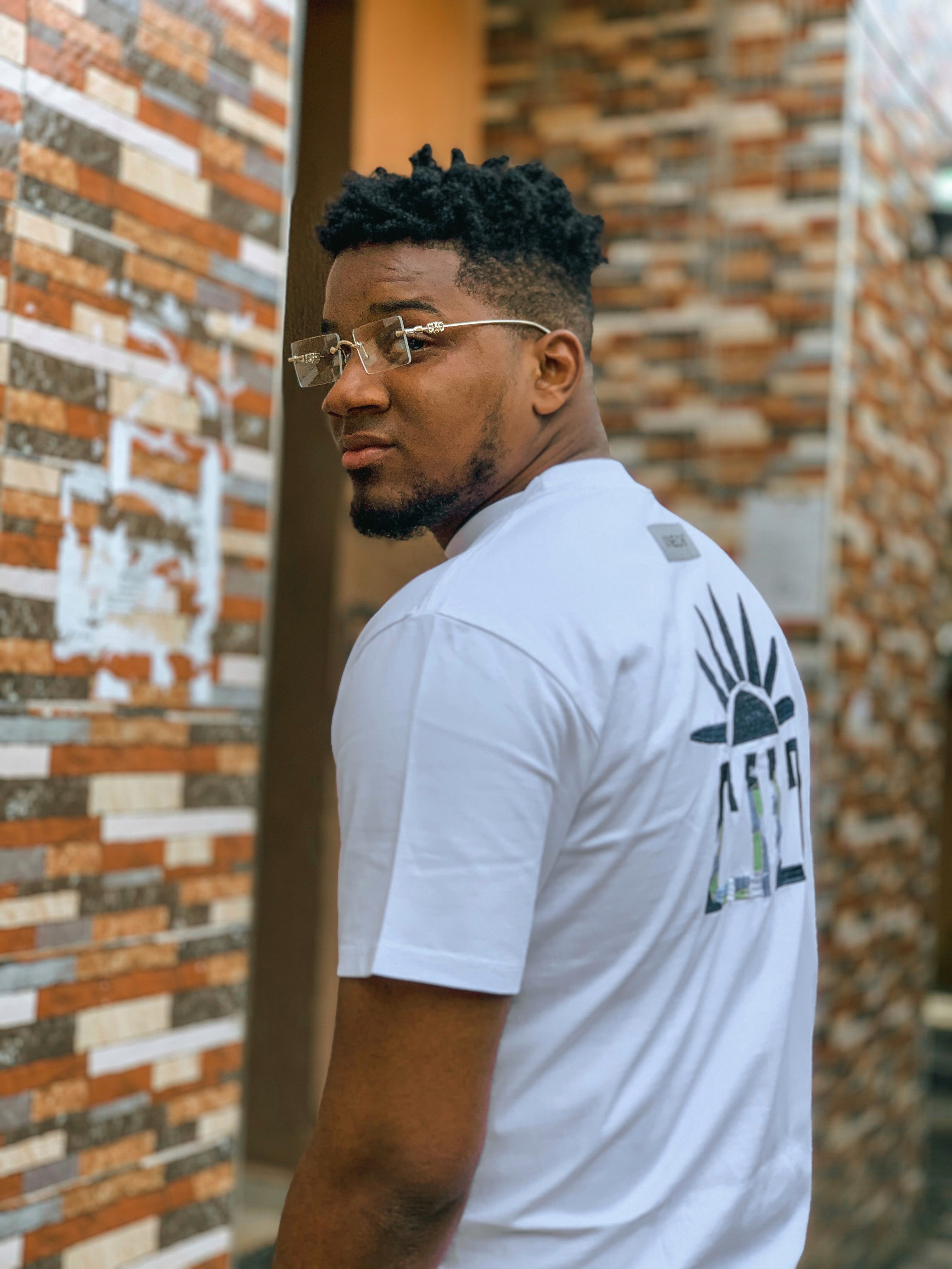 Confident man in trendy eyewear and casual attire posing outdoors.