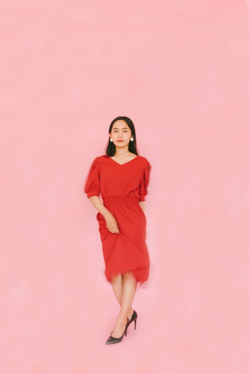 Portrait of a Woman in Red Dress against Pink Background