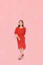 一位穿着红色连衣裙的优雅女性在粉红色背景下的肖像，是现代时尚的缩影