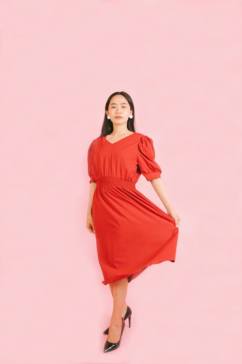 A Woman Wearing a Red Dress in a Pink Background