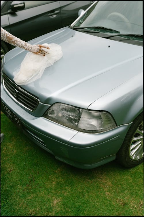 Bride Holding Her Veil on a Car Hood 