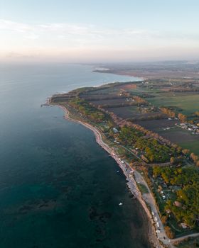 Stunning aerial shot of a coastline with lush greenery and open sea at sunset.