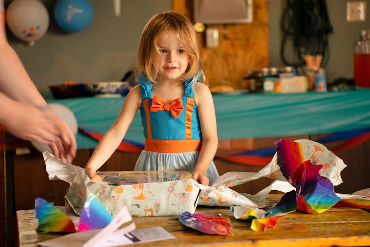 Girl In Dress Opening Her Gift 