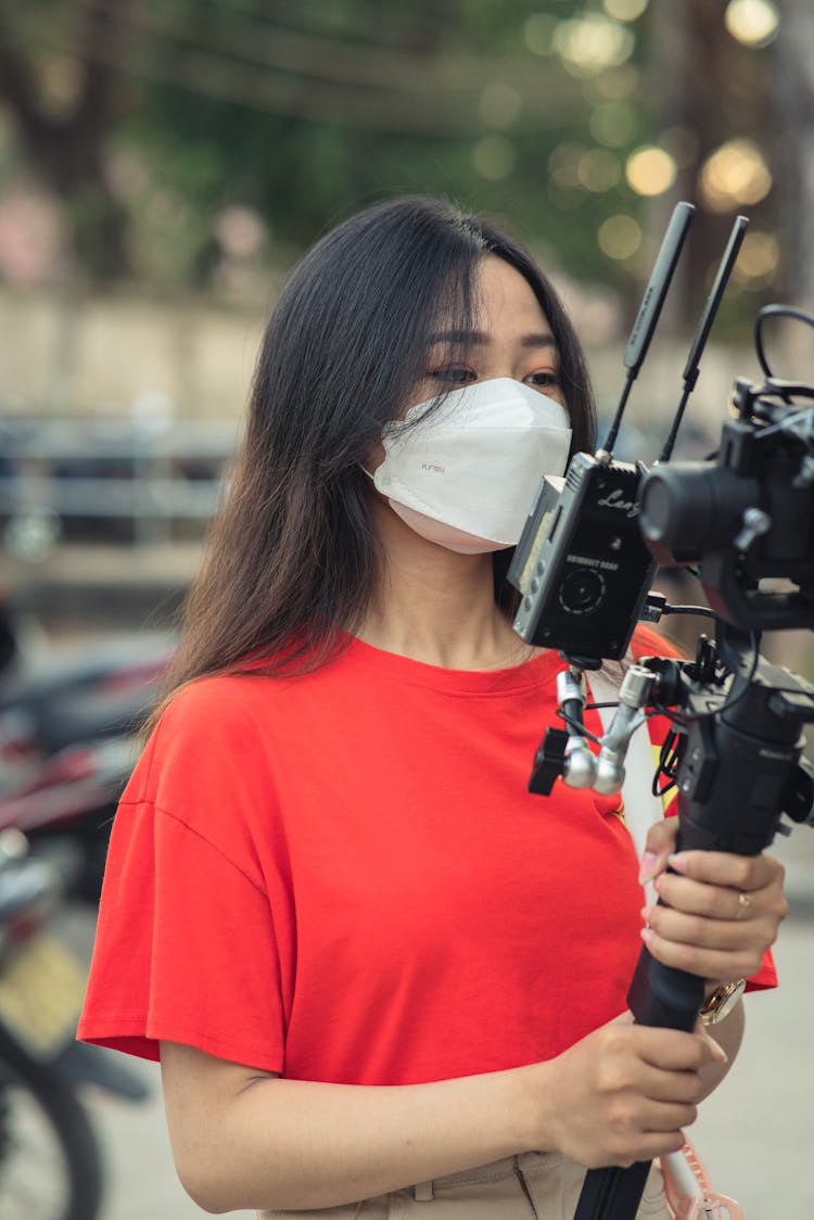 Woman In Mask Holding Tripod