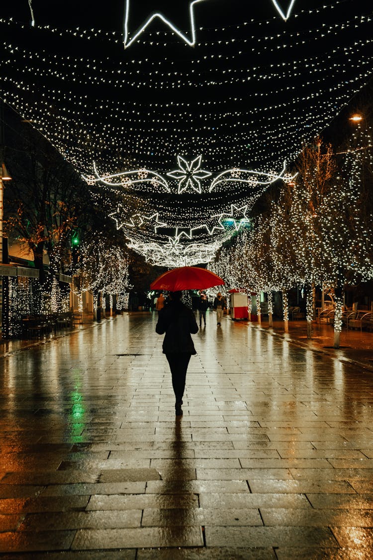 A Person With Red Umbrella Walking On Street During Night Time