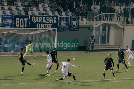 Dynamic action shot of a soccer match in Bakü, Azerbaijan, showcasing players in intense competition.
