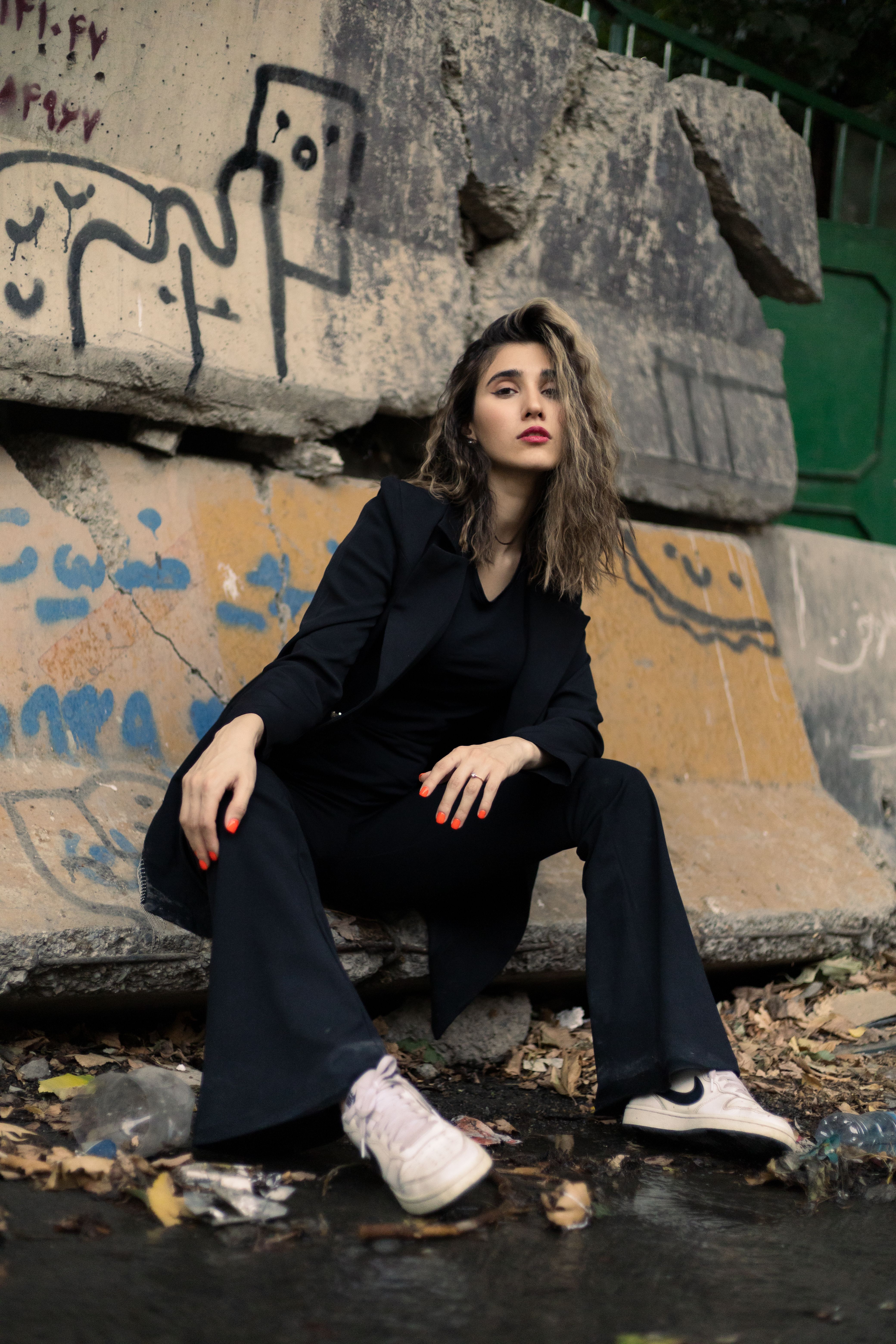 Woman in Black Blazer and Black Pants Sitting on Concrete Wall · Free ...