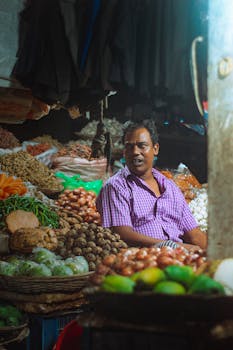 A merchant selling fresh vegetables and produce in a bustling market stall.