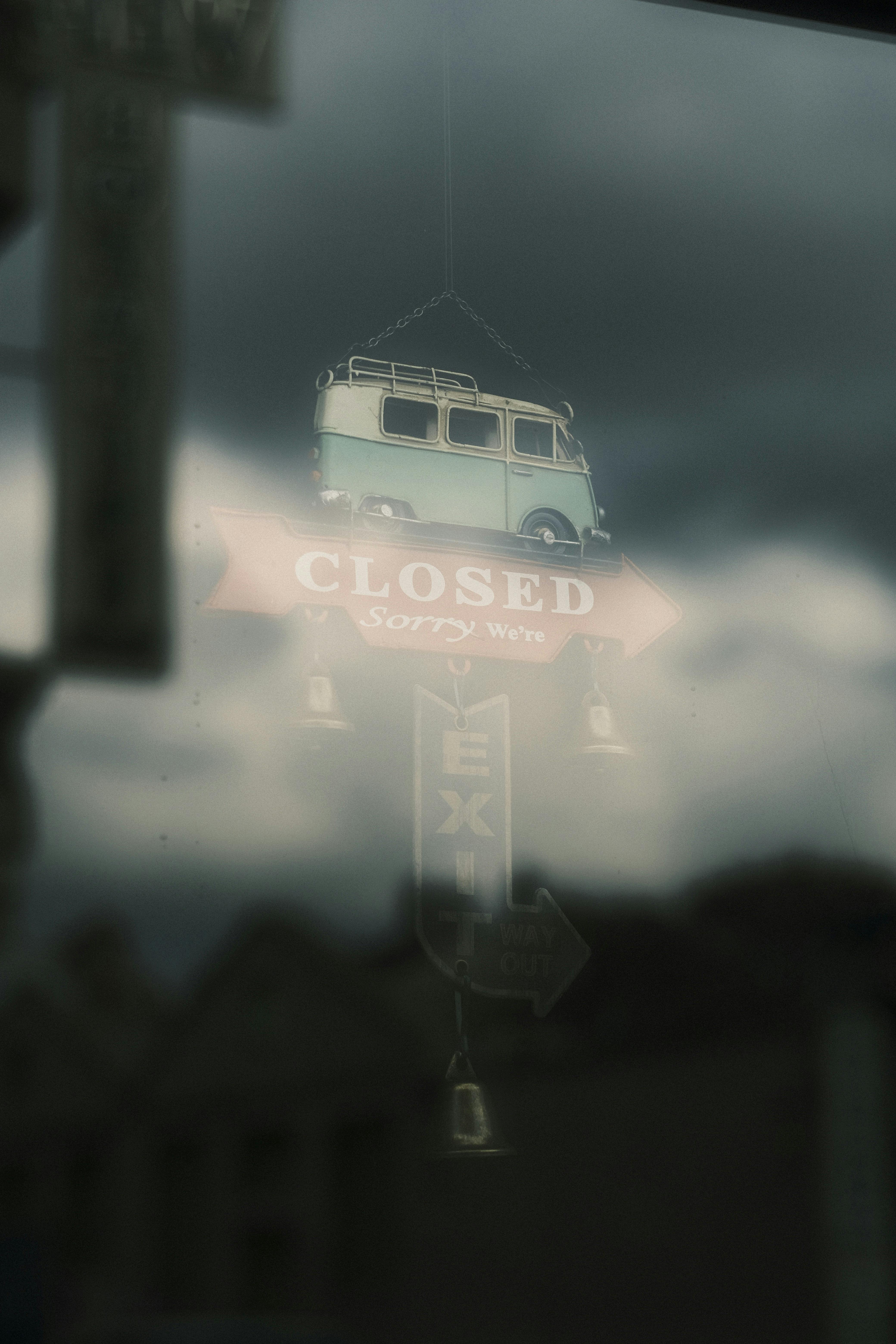 Vintage-style closed sign reflected in window on a cloudy day.