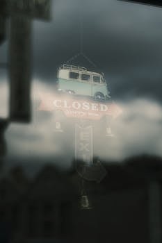Vintage-style closed sign reflected in window on a cloudy day.